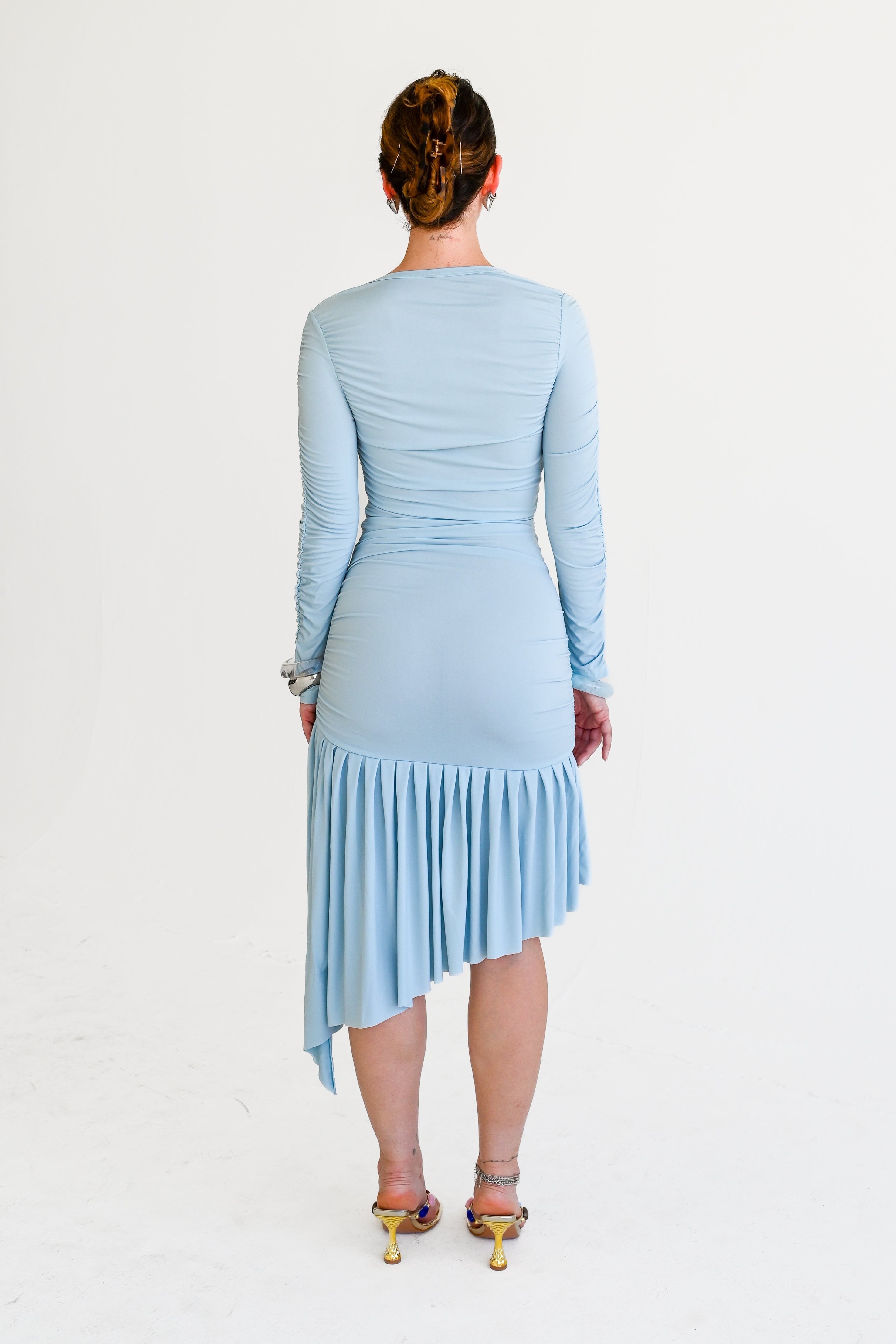 Woman wearing a light blue dress with a pleated skirt on a white background