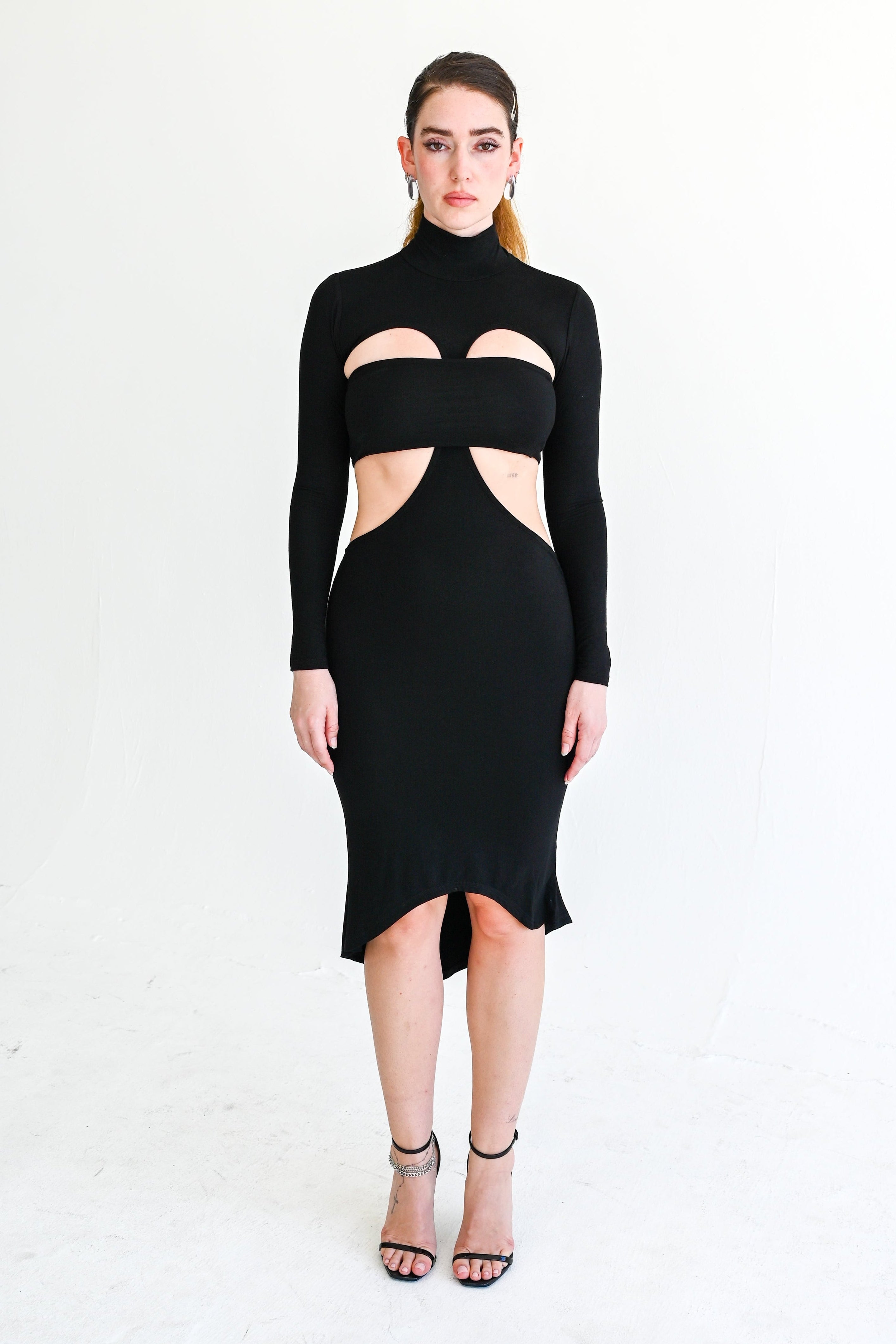 Black cut-out dress worn by a model on a white background