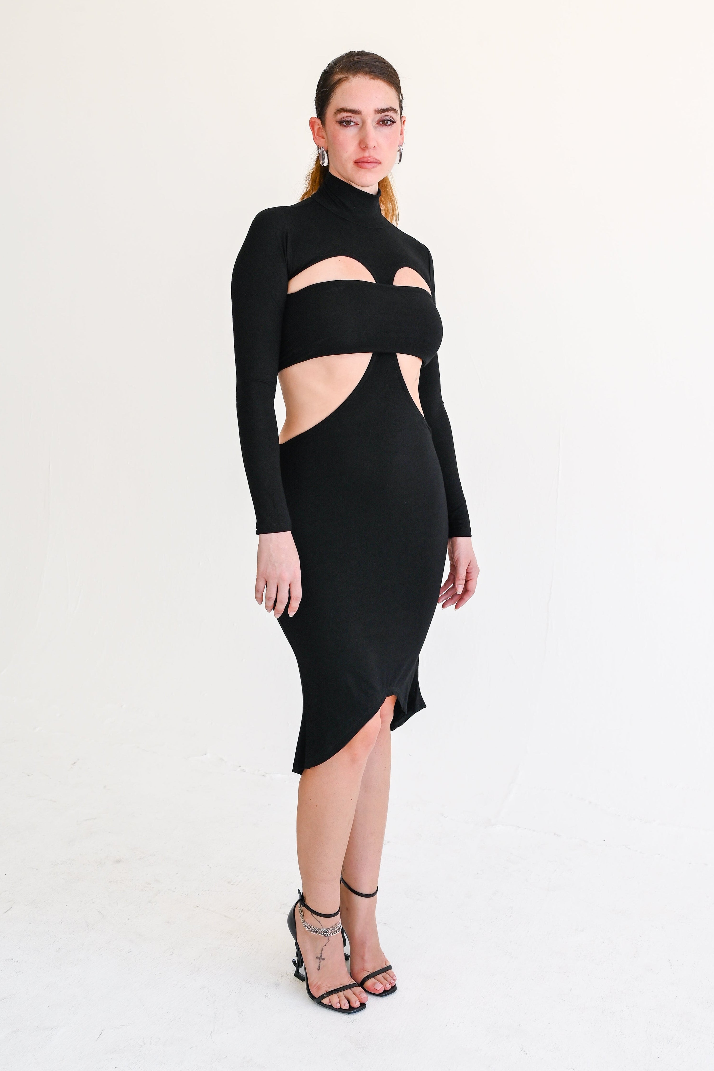 Woman wearing a black cut-out dress on a white background
