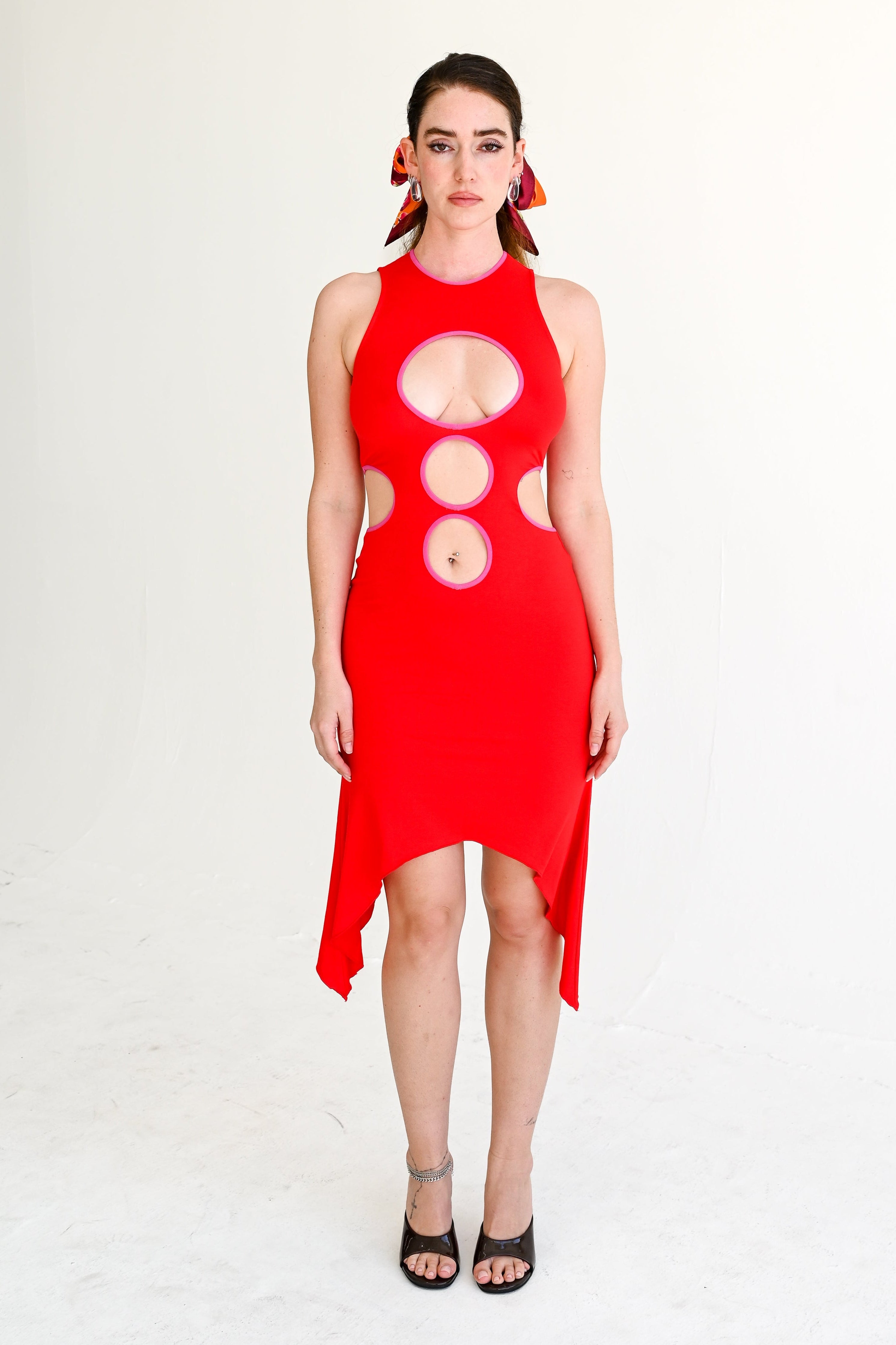 Woman wearing a red dress with cut-out design on a white background