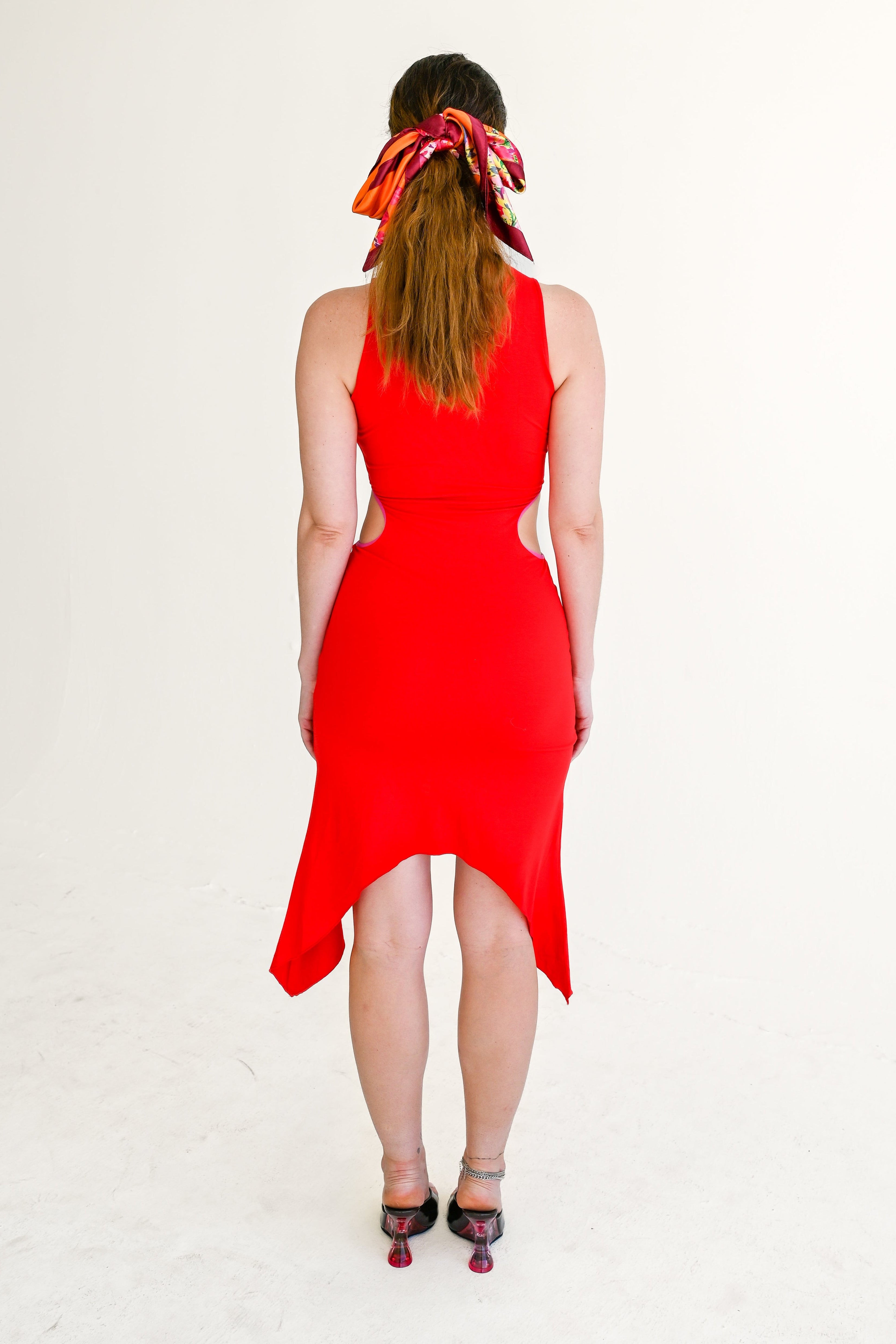 Person wearing a red dress with a headscarf on a white background