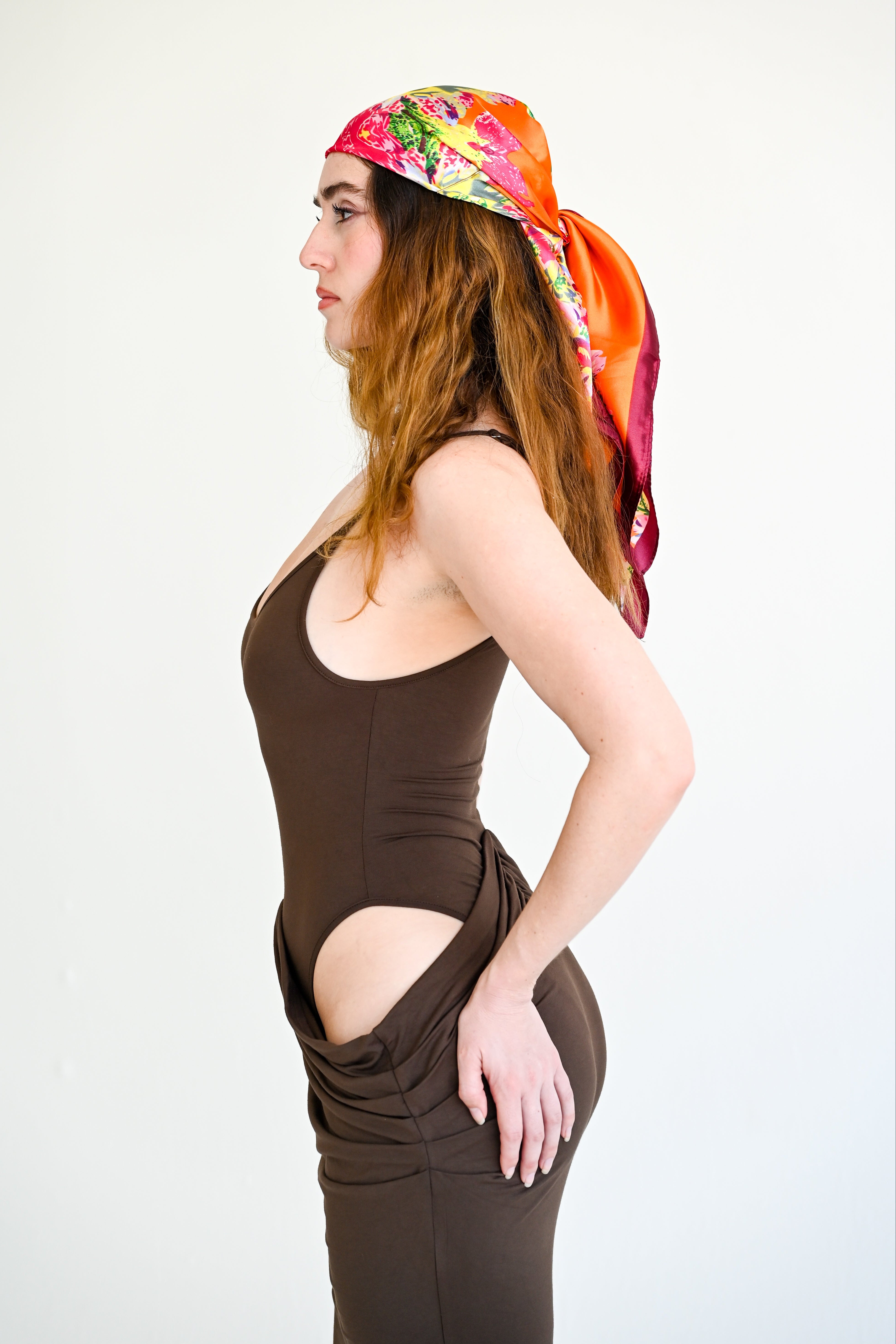 Woman wearing a colorful headscarf and brown dress on a white background
